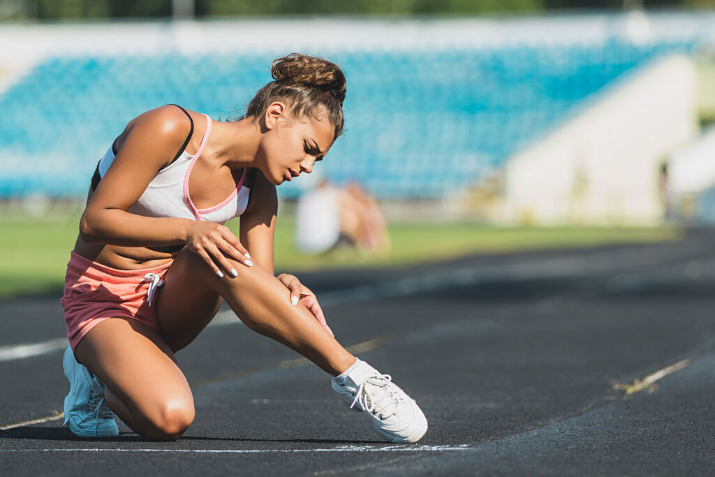mulher em pista de corrida olhando perna